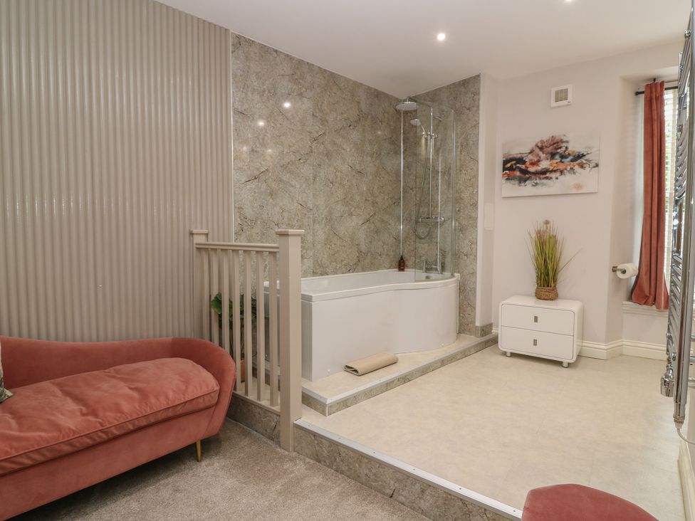 A bathroom with a bathtub, shower, and a couch at 2 Abbey Row, Kelso