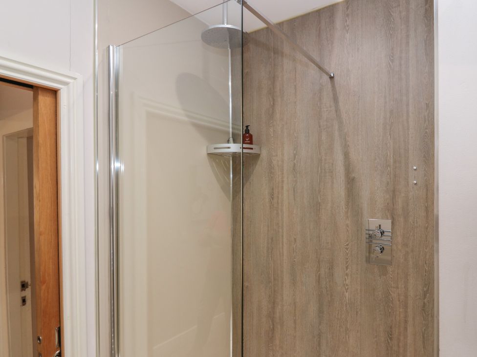 A shower area with a glass panel and wooden wall at 2 Abbey Row Kelso