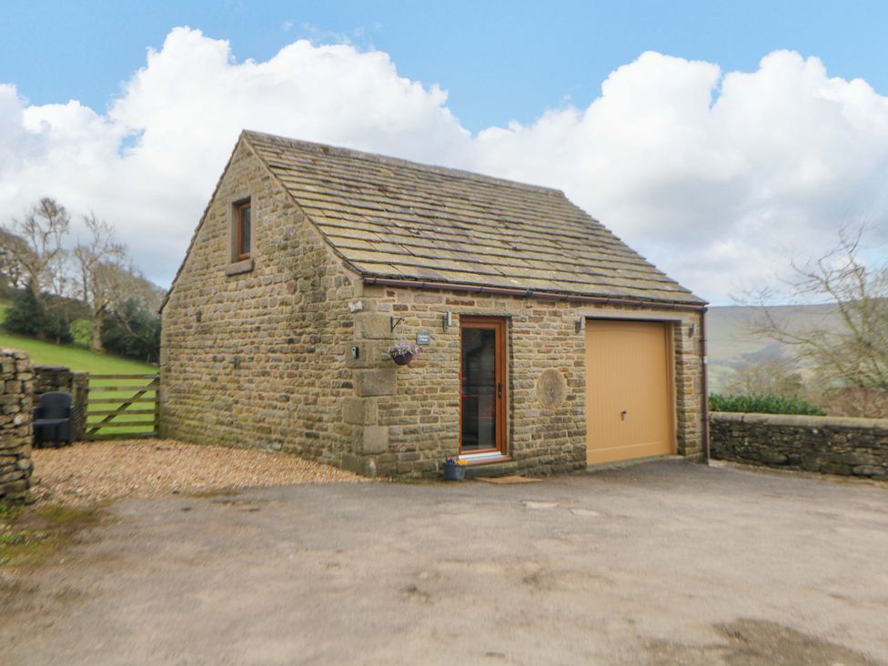 A stone building with a garage door and a window at Charlotte’s Cottage in Hathersage