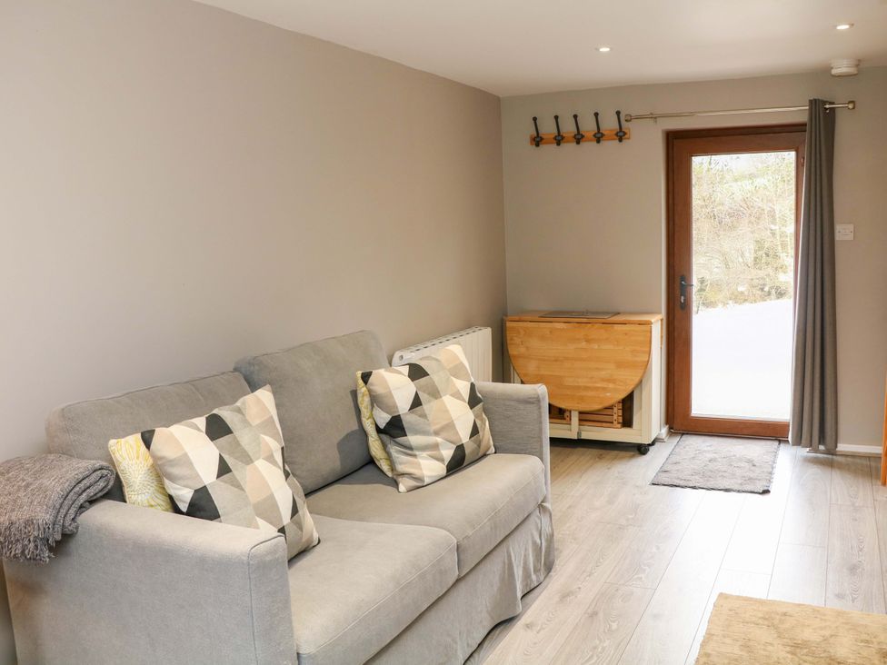 A living room with a couch and door to the outside at Charlotte’s Cottage Hathersage