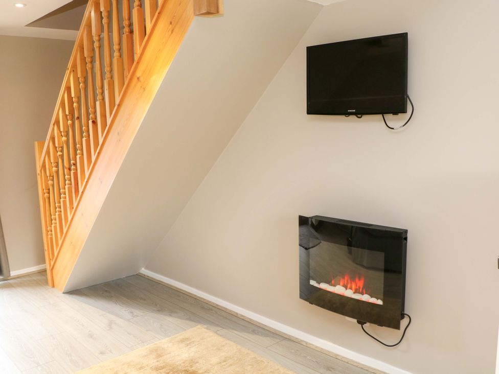 A living room with a TV and electric fireplace at Charlotte’s Cottage in Hathersage