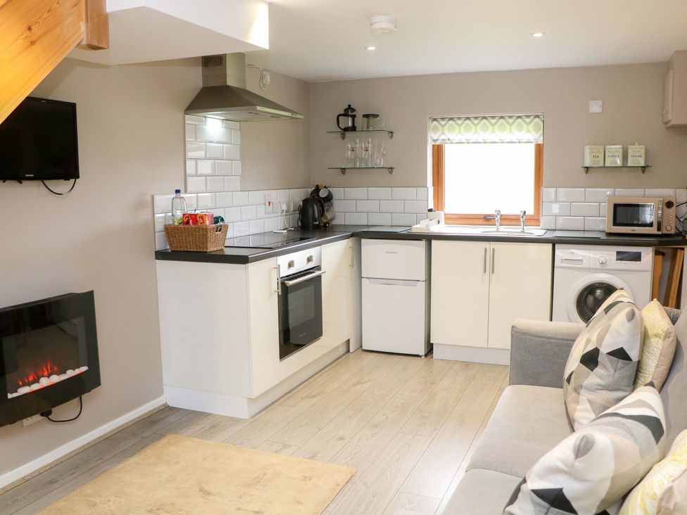 A kitchen with appliances and seating at Charlotte’s Cottage Hathersage