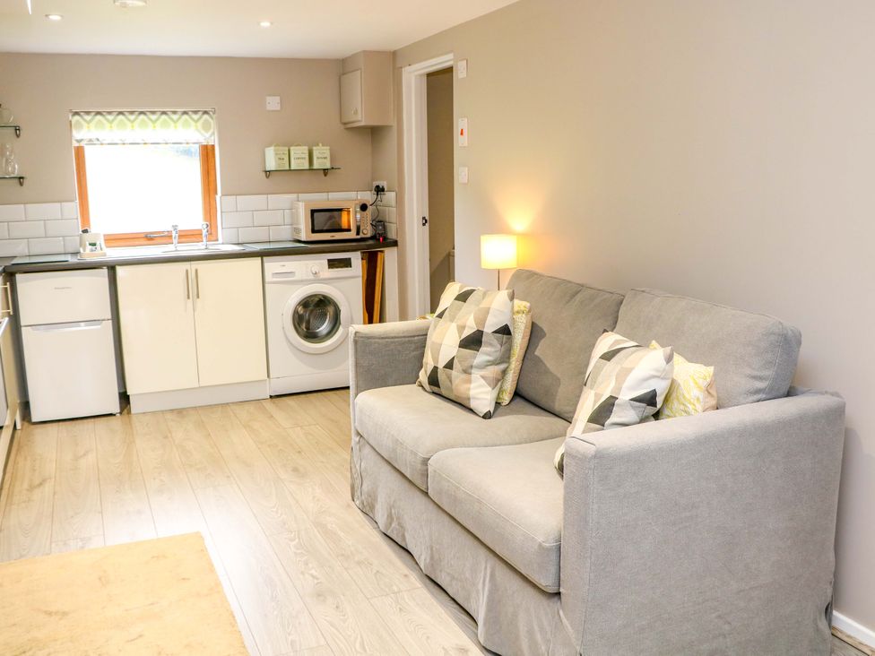 A living room with a sofa and kitchen unit at Charlotte’s Cottage in Hathersage