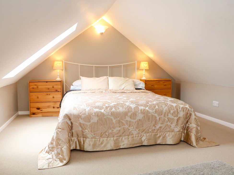 A bedroom with a bed and wooden bedside tables at Charlotte's Cottage in Hathersage