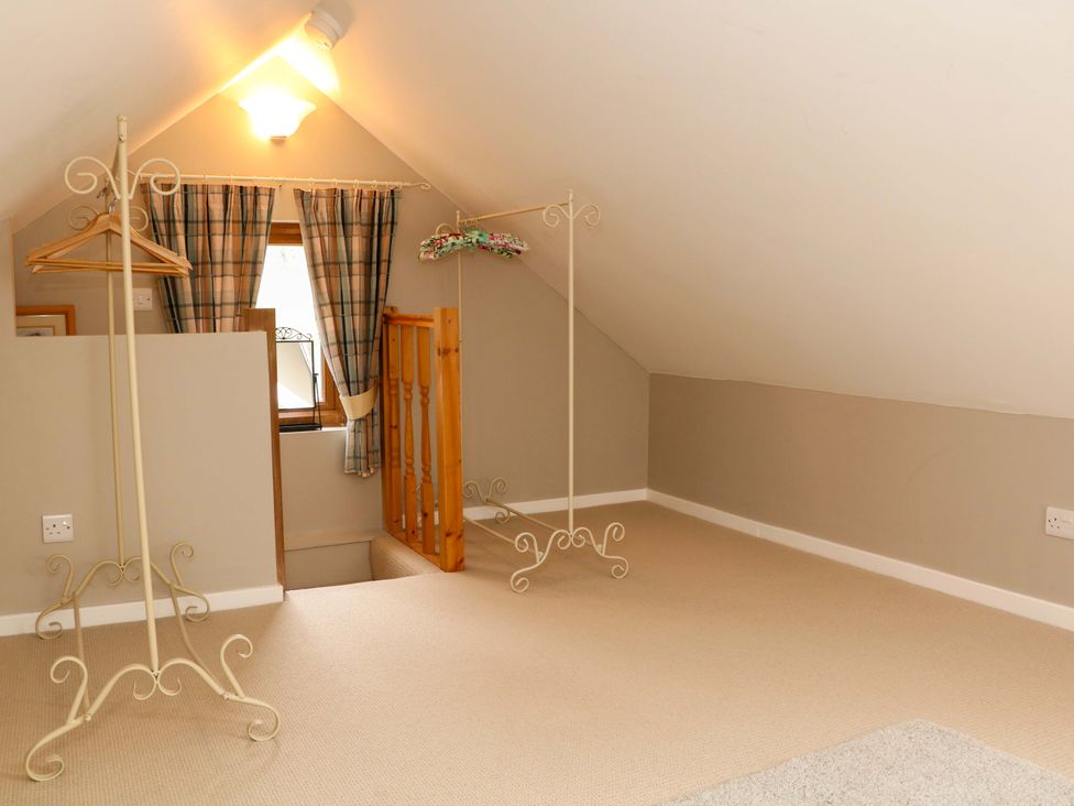 An attic with clothing racks and a window at Charlotte’s Cottage Hathersage