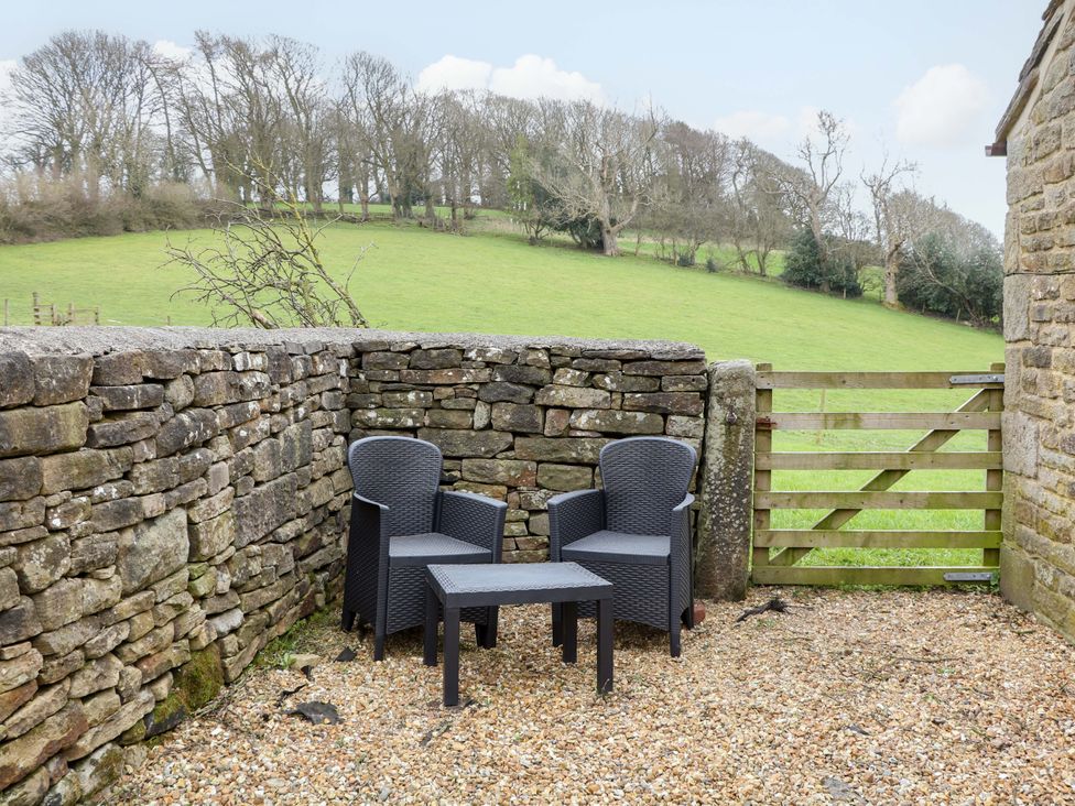 An outdoor seating area with chairs and a table at Charlotte’s Cottage in Hathersage