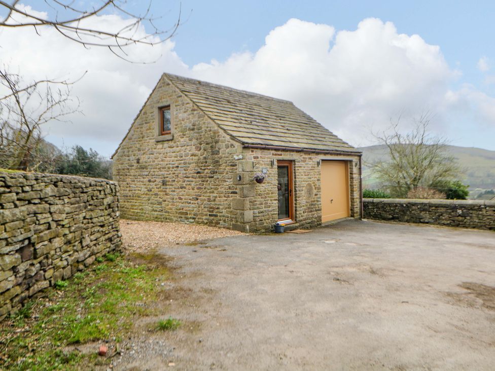 A stone house with a garage door and gravel driveway at Charlotte’s Cottage in Hathersage