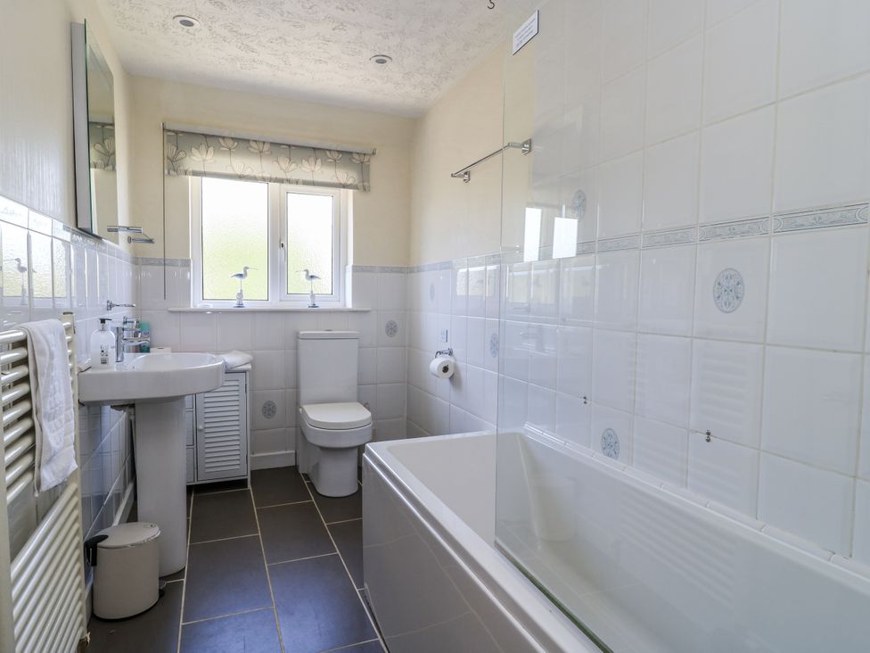 A bathroom with a bathtub, toilet, sink and window at White Stones in Fulbrook, near Burford