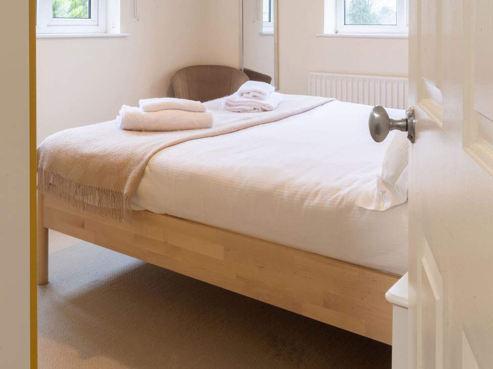 A bedroom with a bed and chair at White Stones, Fulbrook, near Burford