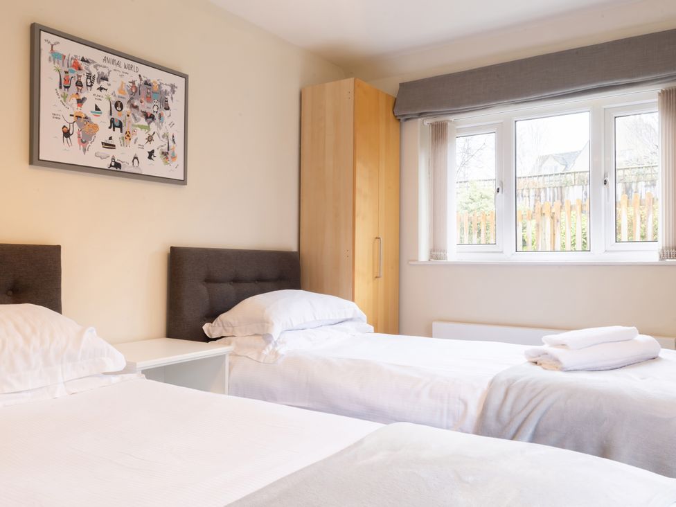 A bedroom with two beds and a wardrobe at White Stones in Fulbrook, near Burford