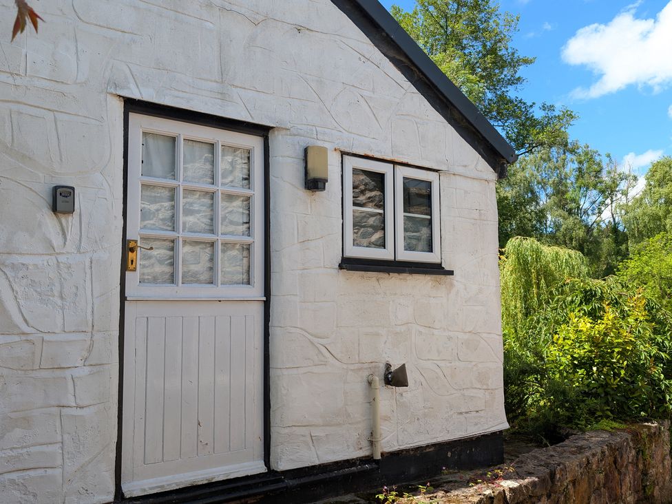 A white exterior wall with a door and window at Little Pandy Cottage Afonwen near Caerwys