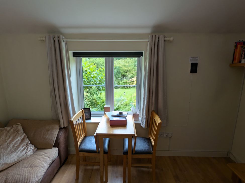 A living room with a table and chairs next to a window at Little Pandy Cottage Afonwen near Caerwys