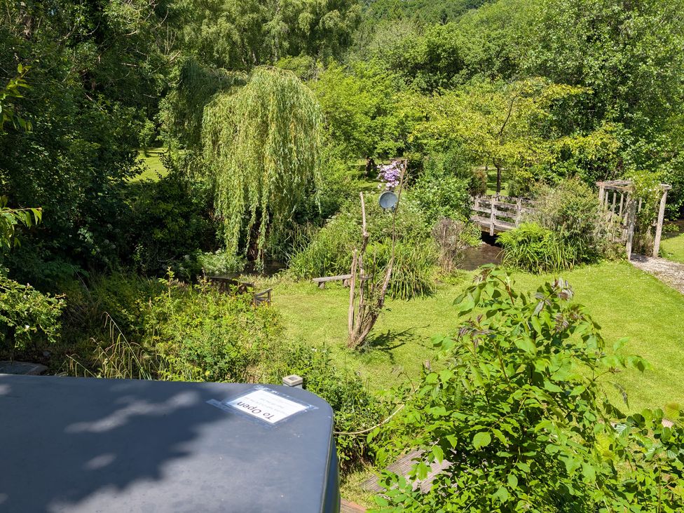 A garden with trees and a bridge at Little Pandy Cottage Afonwen near Caerwys