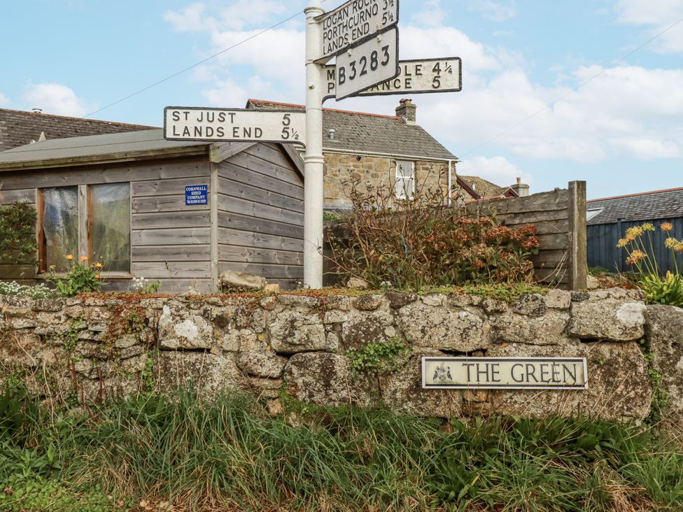 A house with a stone wall and signpost at The Green