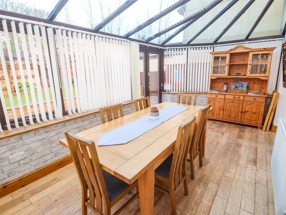 A conservatory with a dining table and sideboard at Cherry Tree House in Penzance