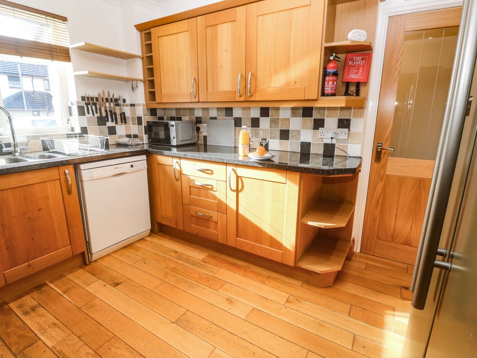 A kitchen with wooden cabinets and appliances at Cherry Tree House in Penzance