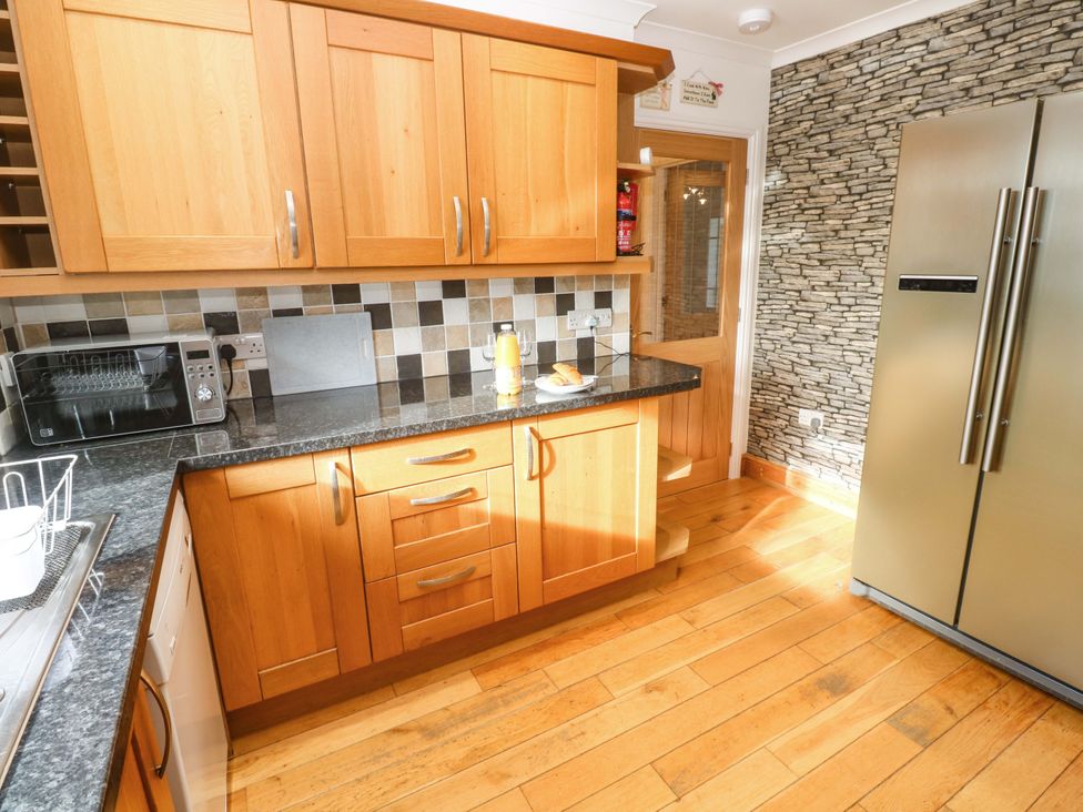 A kitchen with wooden cabinets and a microwave at Cherry Tree House in Penzance