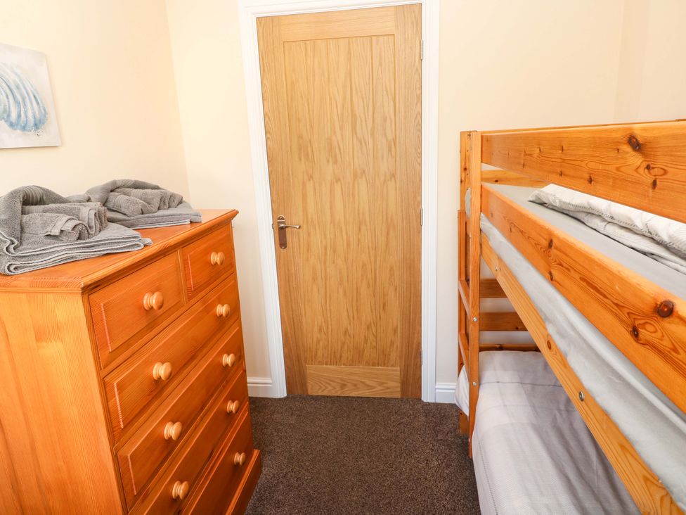 A bedroom with a bunk bed and a wooden dresser at Cherry Tree House in Penzance