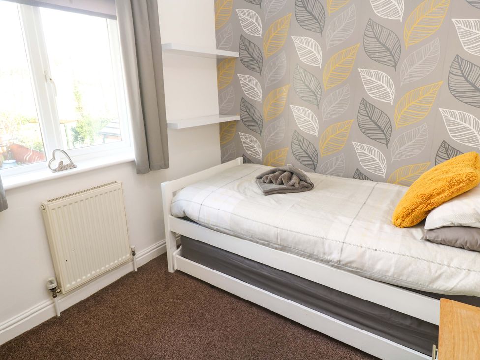 A bedroom with a bed and a shelf at Cherry Tree House in Penzance