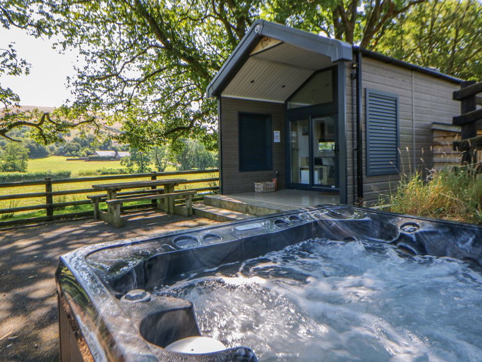 A hot tub with a bench and table at Oak Tree View Nantmel near Rhayader