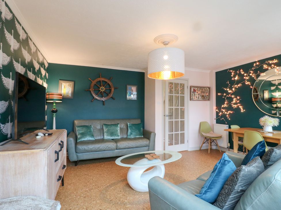 A living room with a sofa, coffee table and dining area at Coastguard Cottage in Rye
