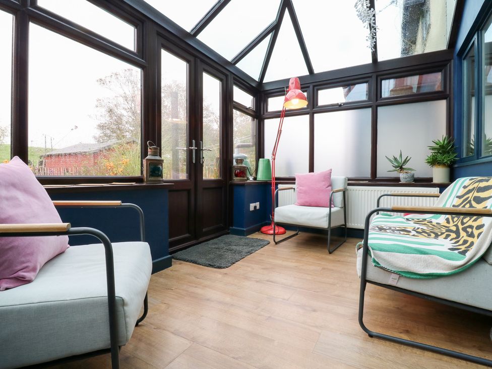 A conservatory with chairs and a lamp at Coastguard Cottage in Rye