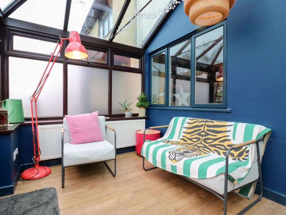 A conservatory with a lamp and chairs at Coastguard Cottage in Rye