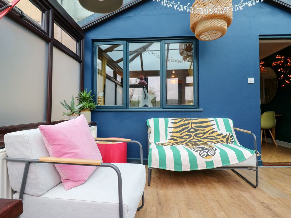A conservatory with seating and plants at Coastguard Cottage in Rye