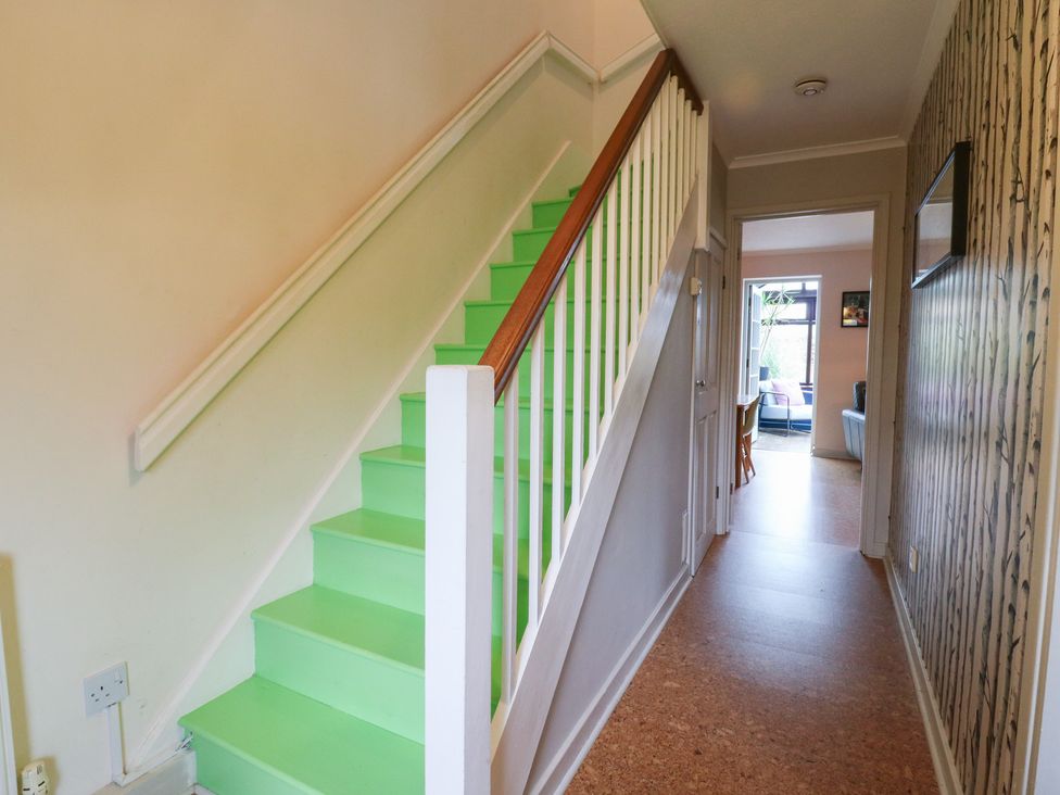 A hallway with stairs leading upstairs at Coastguard Cottage in Rye