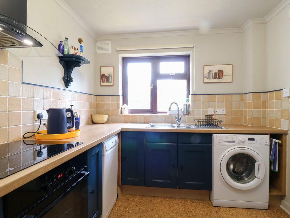 A kitchen with a sink, kettle, and washing machine at Coastguard Cottage in Rye