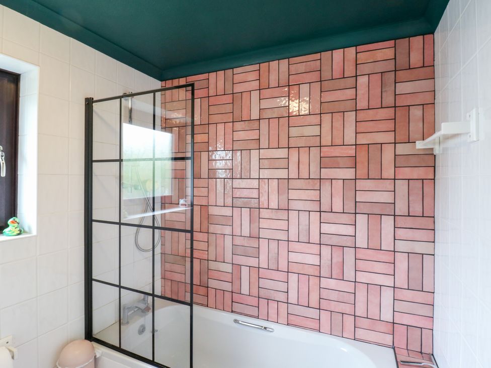 A bathroom with a bathtub and glass shower enclosure at Coastguard Cottage, Rye