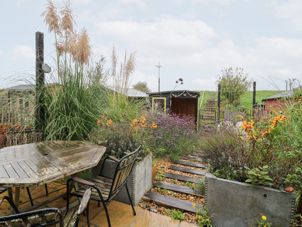 A garden with a table and chairs surrounded by flowers at Coastguard Cottage in Rye
