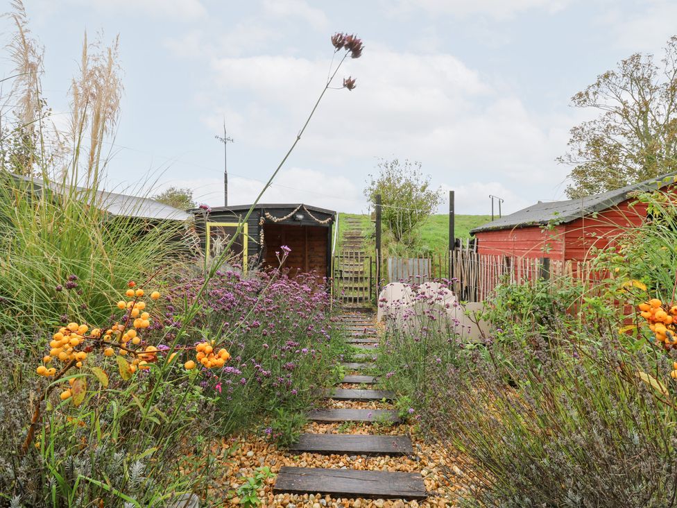 A garden with a wooden path and flower beds at Coastguard Cottage in Rye