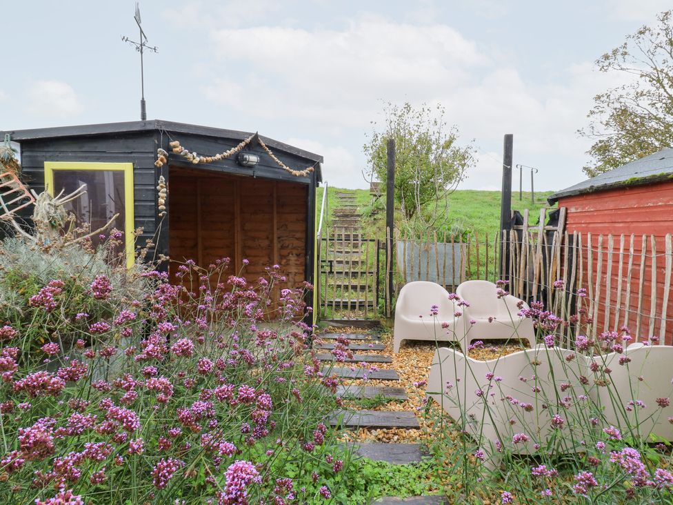 A garden with chairs, flowers, and a shed at Coastguard Cottage Rye