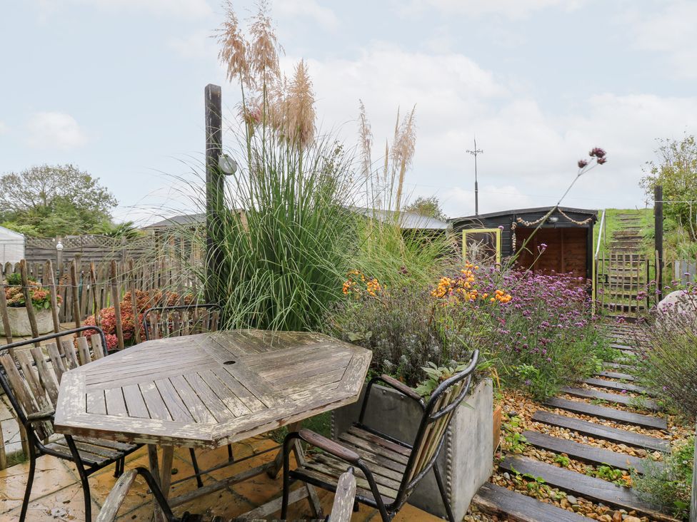 A garden with a table and chairs surrounded by plants at Coastguard Cottage in Rye