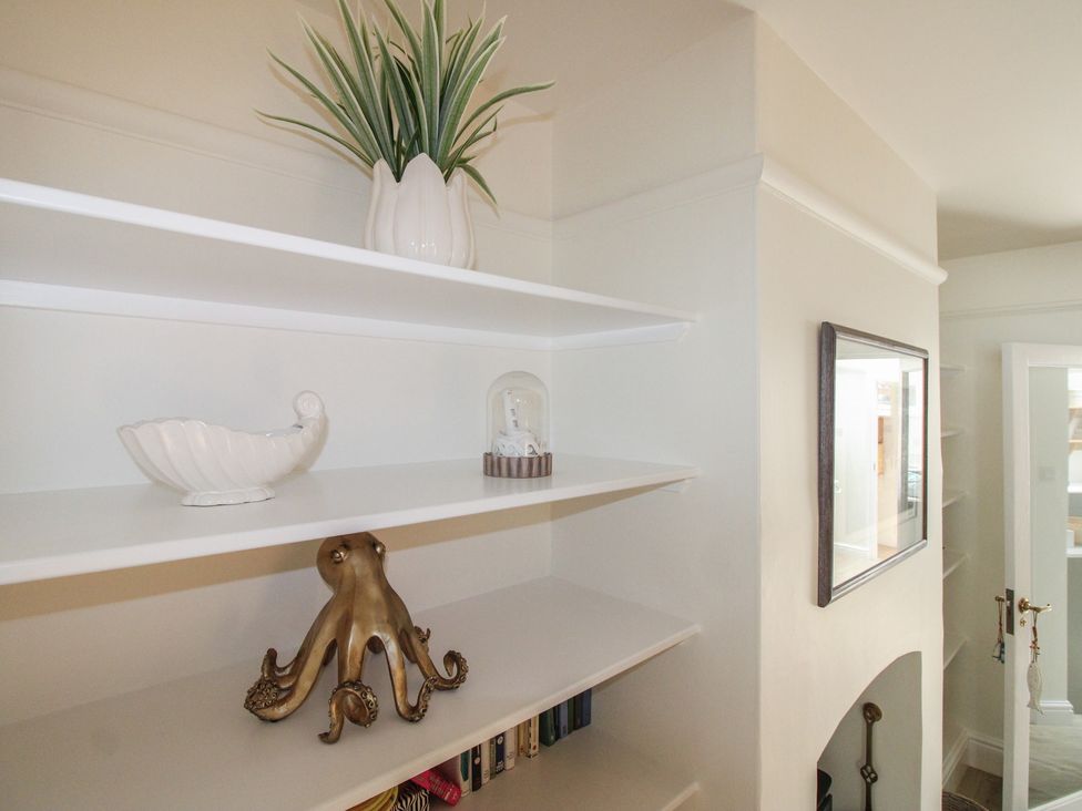 Shelves with a plant, shell, octopus, and picture frame at Home in Salcombe