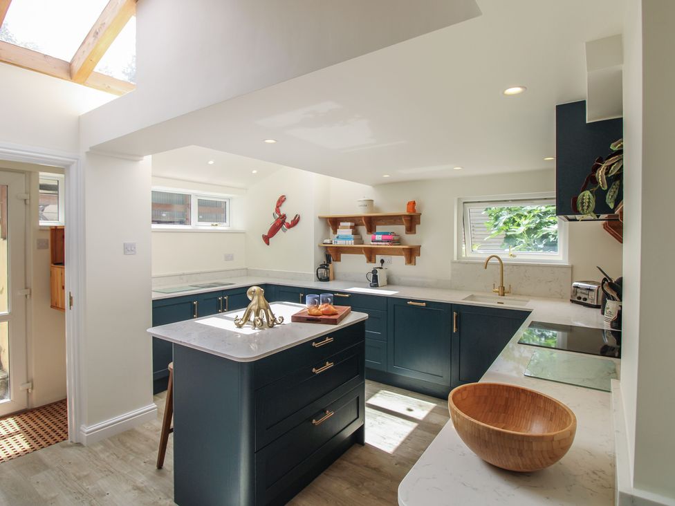 A kitchen with a central island and shelves at Home in Salcombe