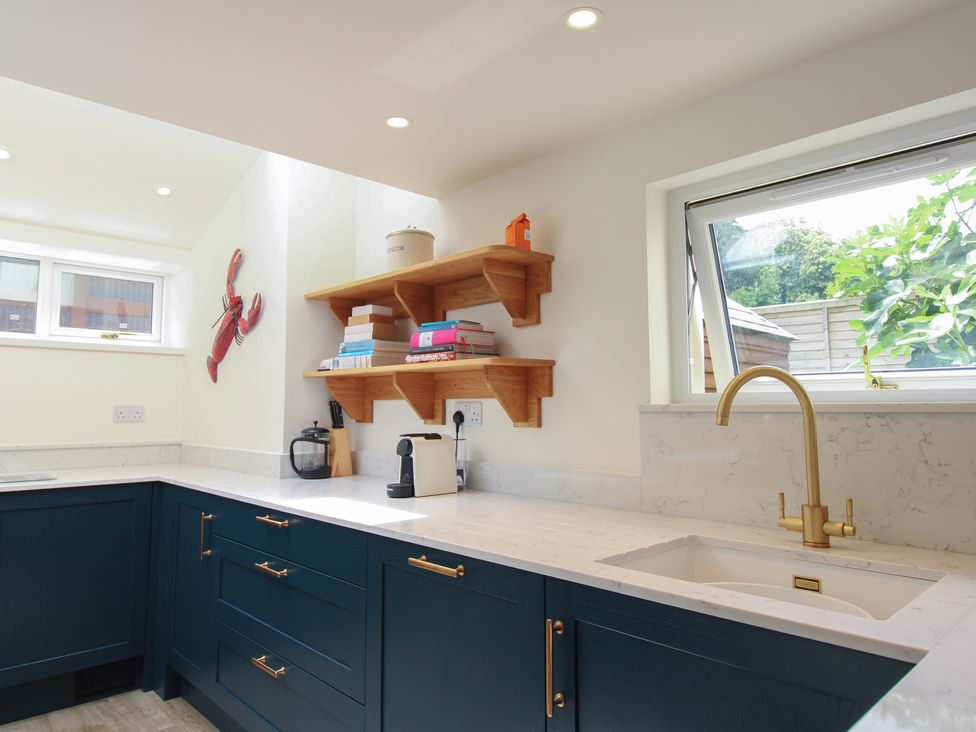A kitchen with a sink and shelves at Home in Salcombe