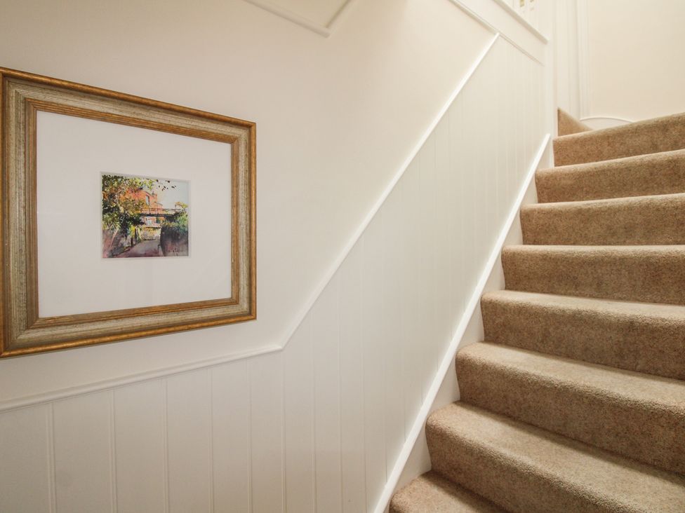 A staircase with carpet and framed artwork at Home in Salcombe