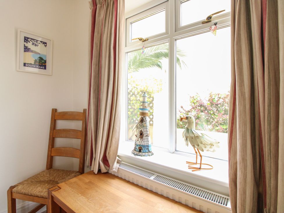 A dining room with a chair and table by the window at Home in Salcombe