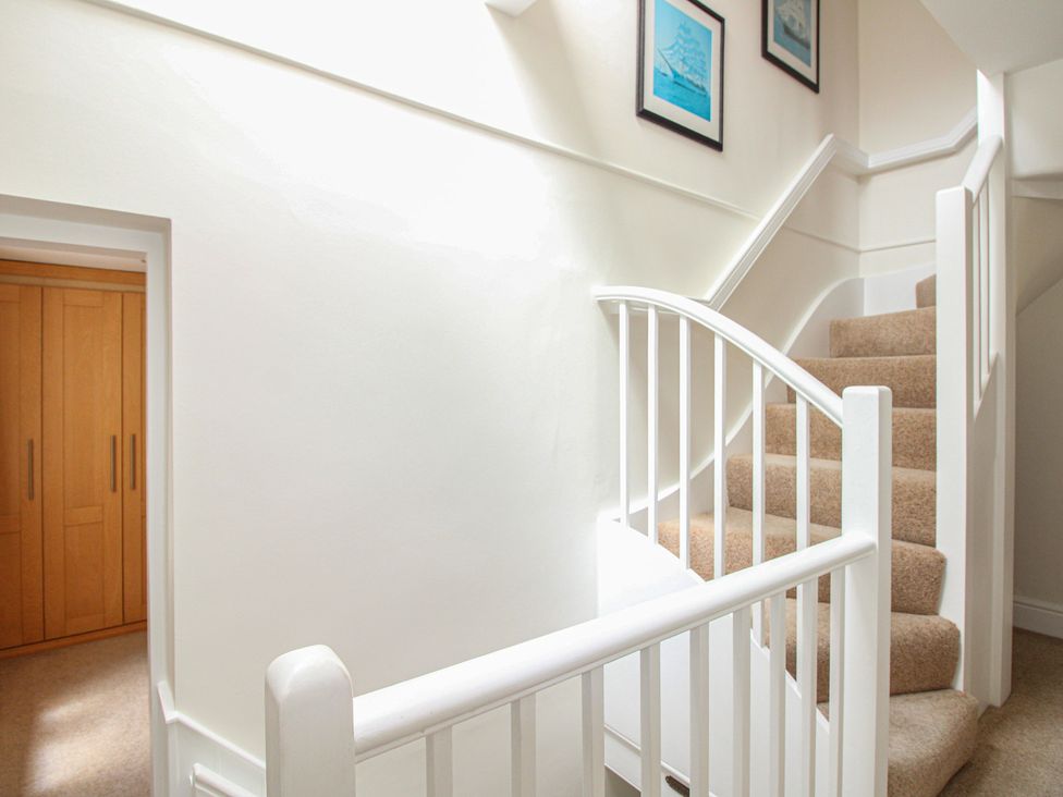 A staircase with a handrail in a hallway at Home in Salcombe