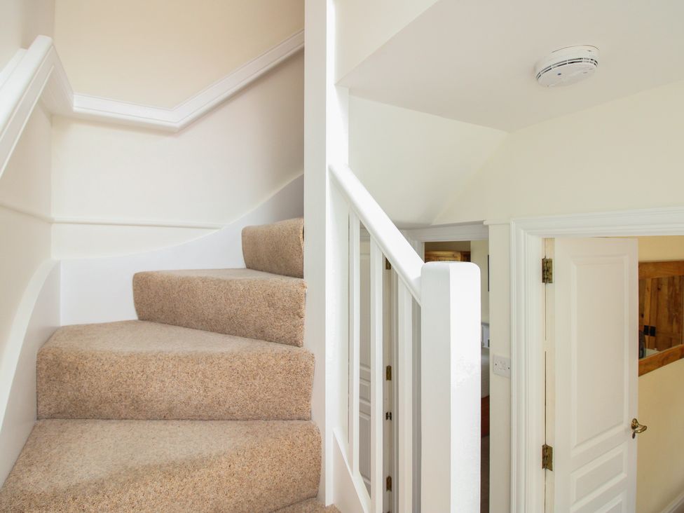 A staircase with a handrail and a door at Home in Salcombe