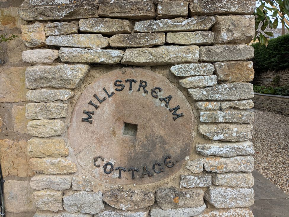 A stone wall with a sign reading Mill Stream Cottage at Mill Stream Cottage in Lower Slaughter near Bourton-On-The-Water