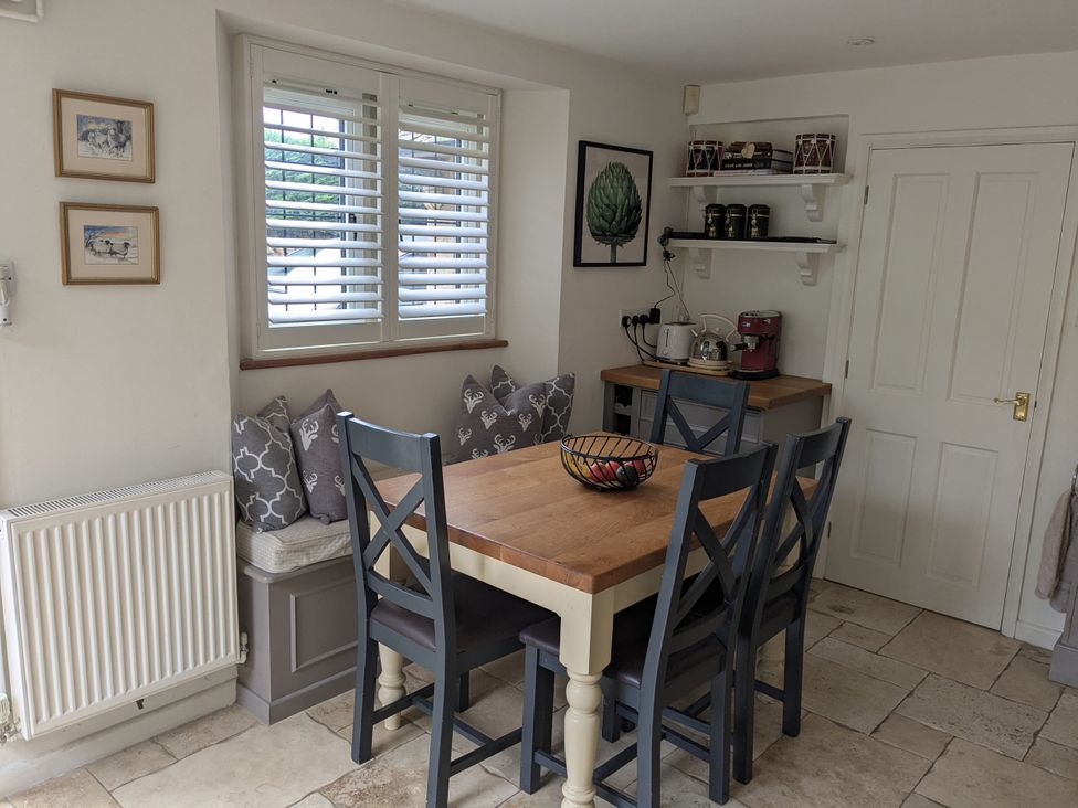 A kitchen with a table and chairs at Mill Stream Cottage in Lower Slaughter near Bourton-On-The-Water