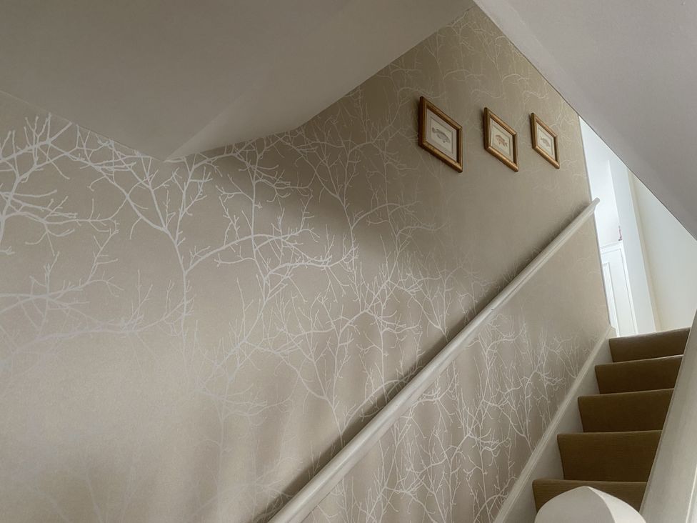 A staircase with framed pictures on the wall at Mill Stream Cottage Lower Slaughter near Bourton-On-The-Water