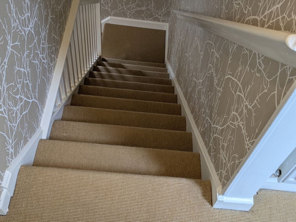 A staircase with carpet and wallpaper at Mill Stream Cottage in Lower Slaughter near Bourton-On-The-Water