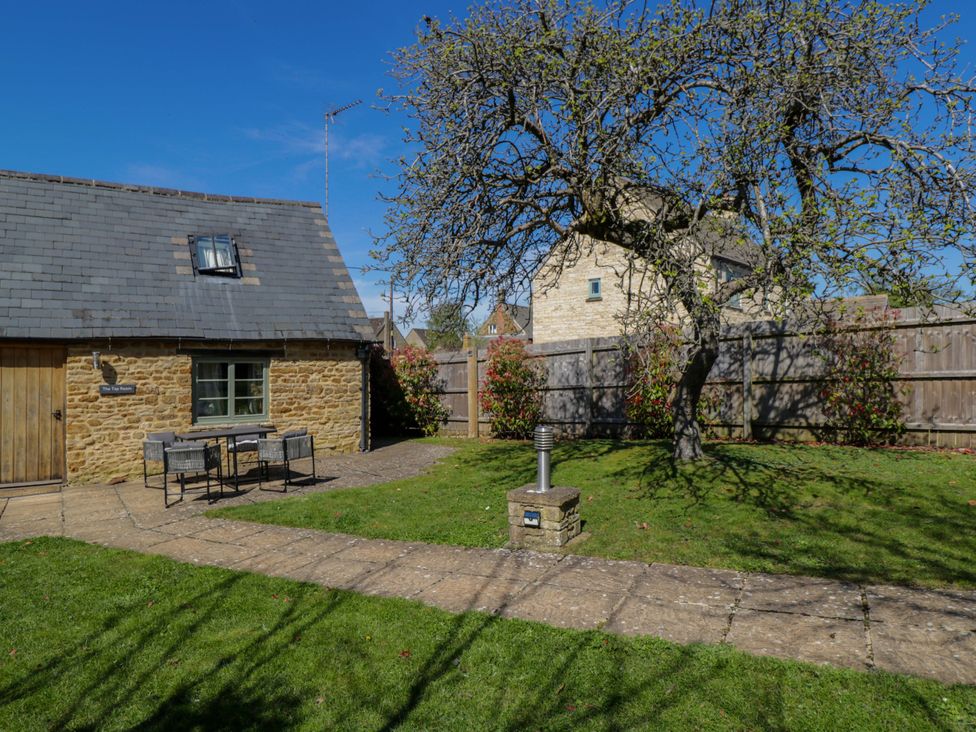 An outdoor area with a cottage, tree, table, and chairs at The Tap Room in Kingham