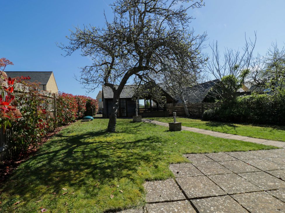 A garden with a tree and pathway at The Tap Room in Kingham
