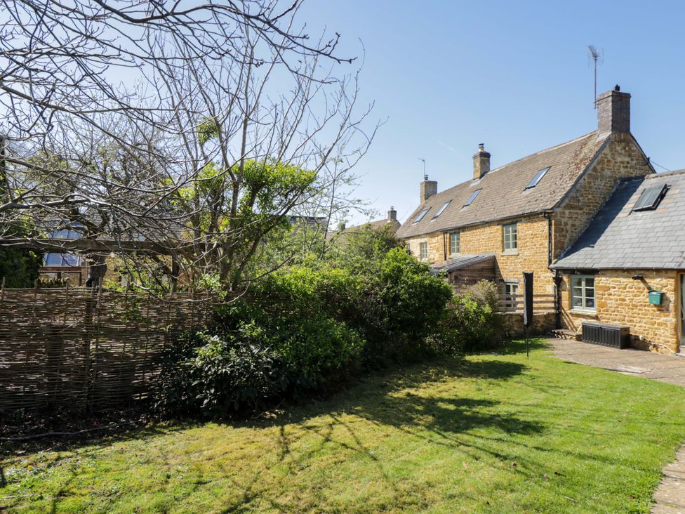 A garden with a house and tree at The Tap Room in Kingham