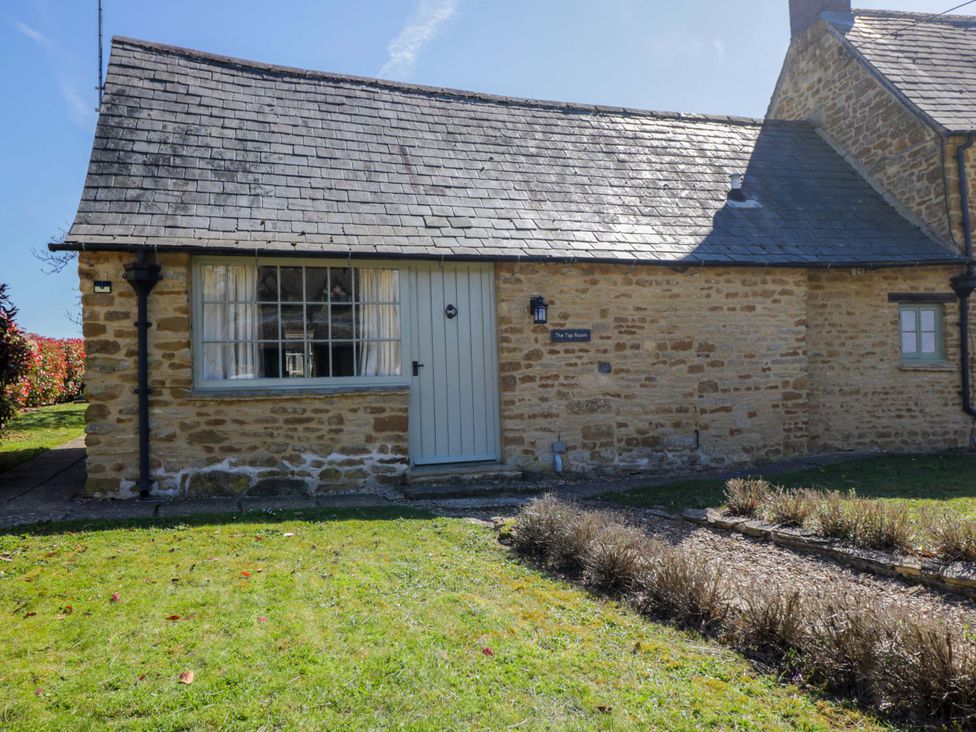 A stone cottage with a blue door and window at The Tap Room in Kingham